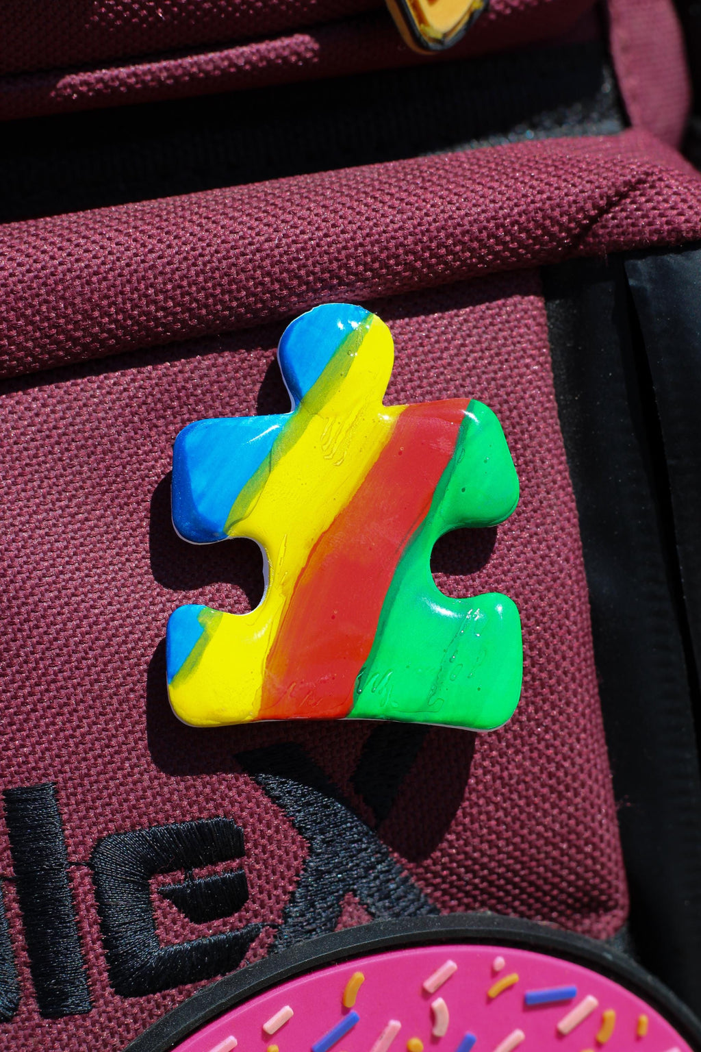 Colorful puzzle piece-shaped pin on a red bag