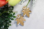 Latte brown floral earrings on a marble surface with greenery