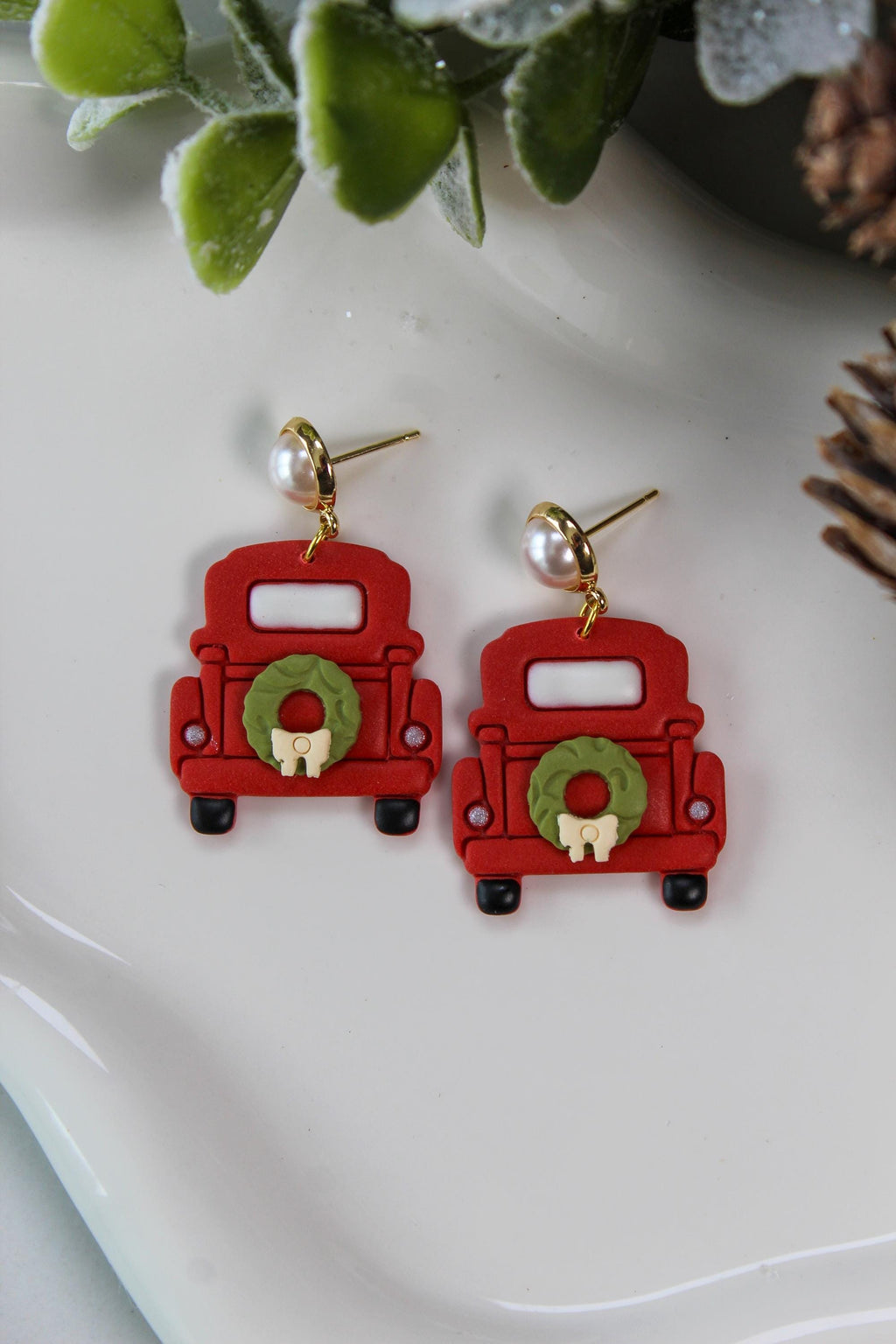 Red truck earrings with wreaths on a white surface