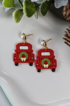 Red truck earrings with wreaths on a white surface