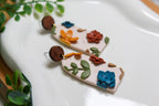 Arch-shaped earrings with floral designs on a white surface