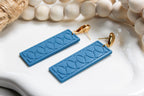 Blue textured earrings with gold hooks on a white surface with beads