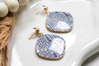 Pair of blue and white patterned earrings on a white dish.