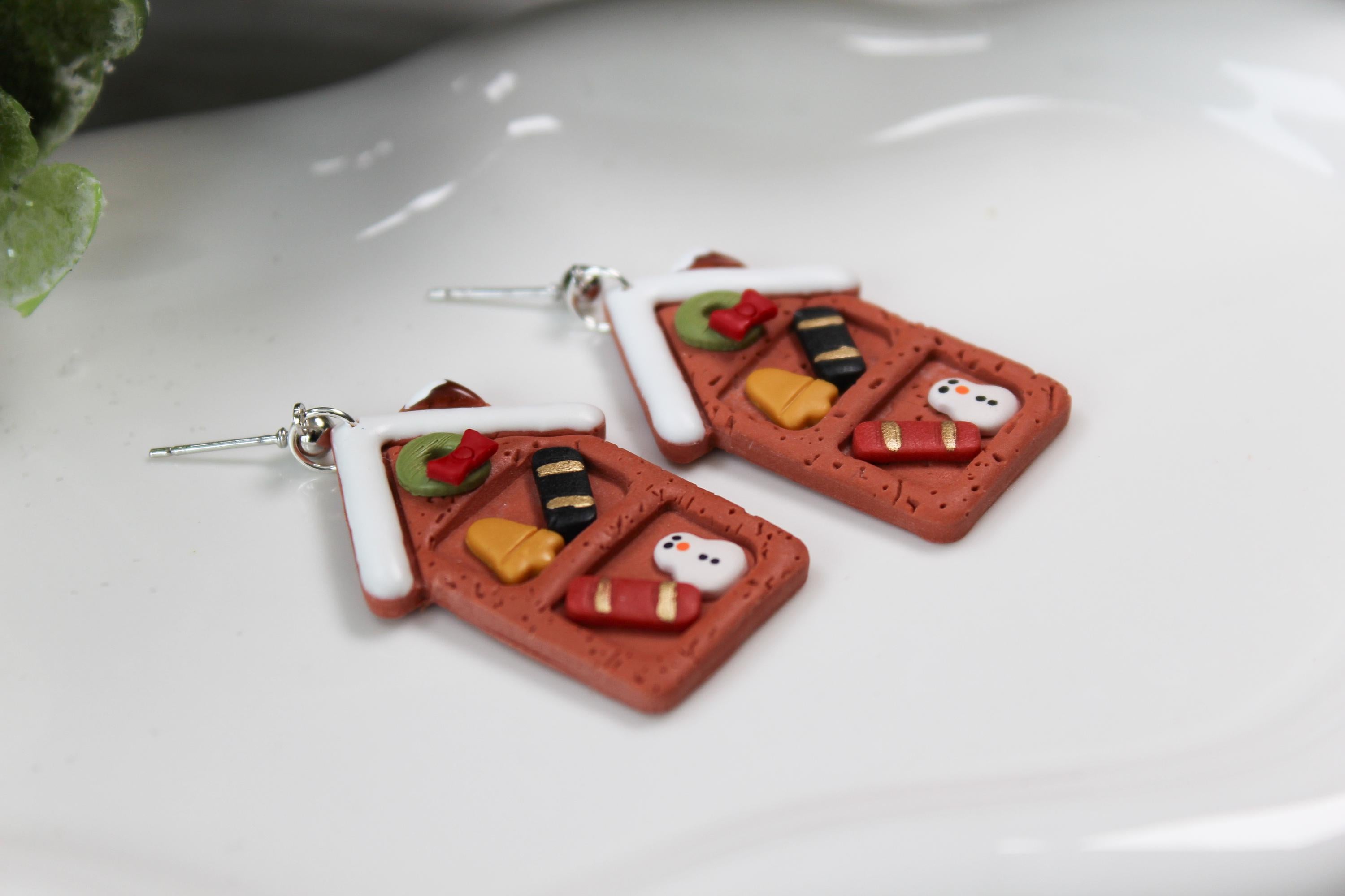 Festive Gingerbread house earrings on a white surface