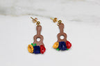 Pair of earrings shaped like guitars with floral tops on a light background