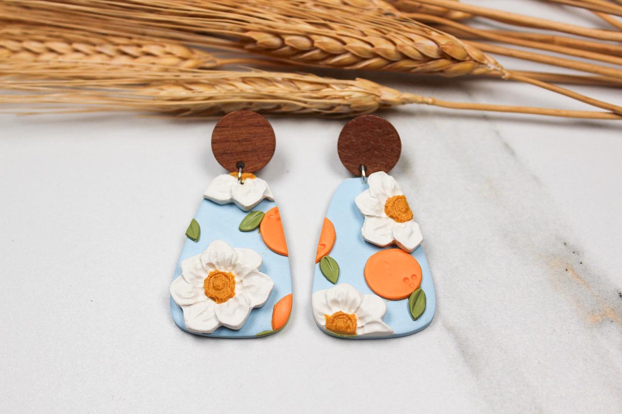 Floral and peach earrings with wooden accents on a light background