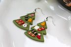 Green leaf-shaped earrings with colorful decorations on a white surface