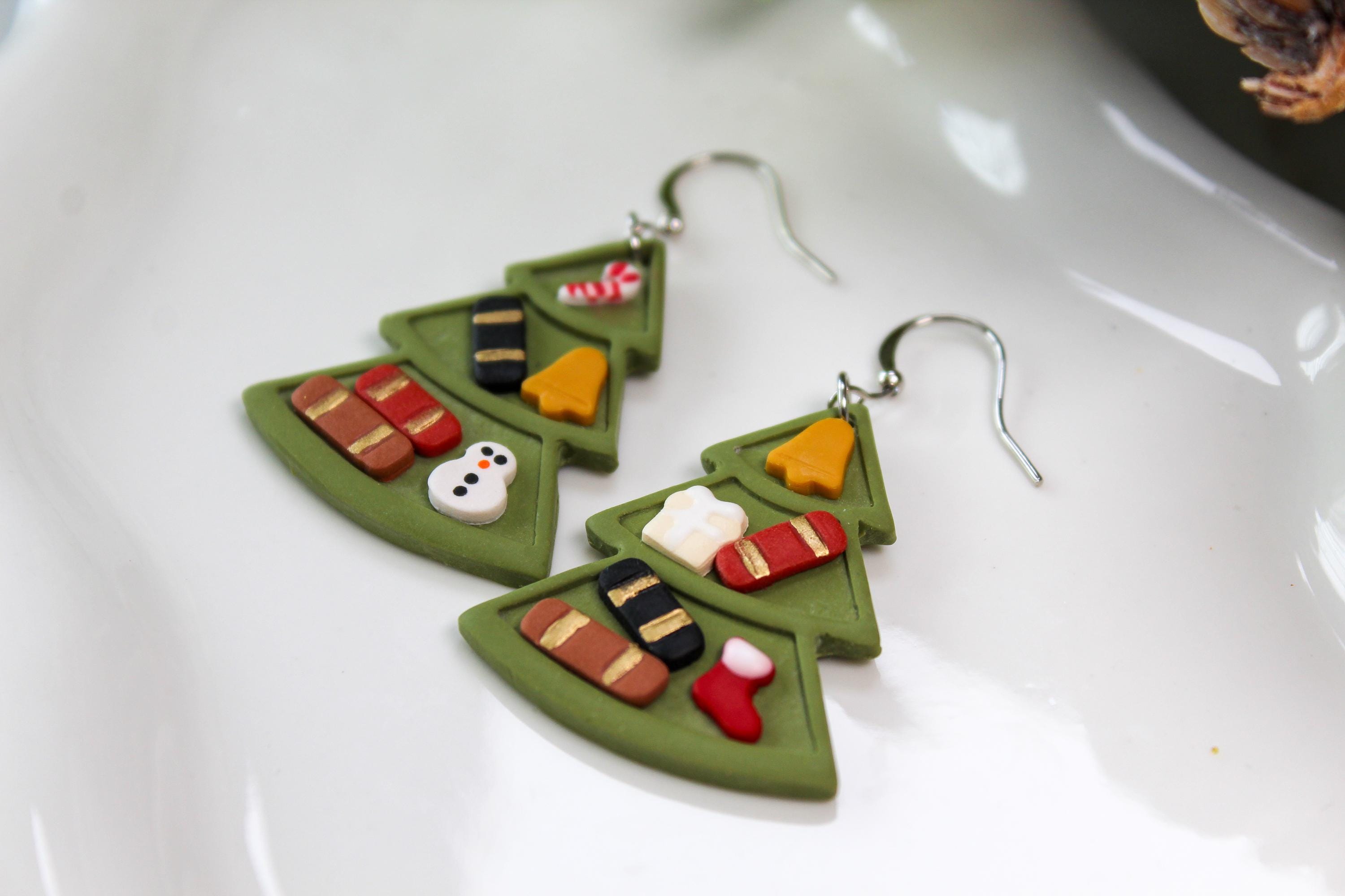 Green leaf-shaped earrings with colorful decorations on a white surface