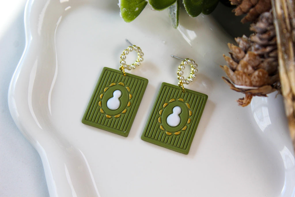 Green earrings with white snowman on a white tray