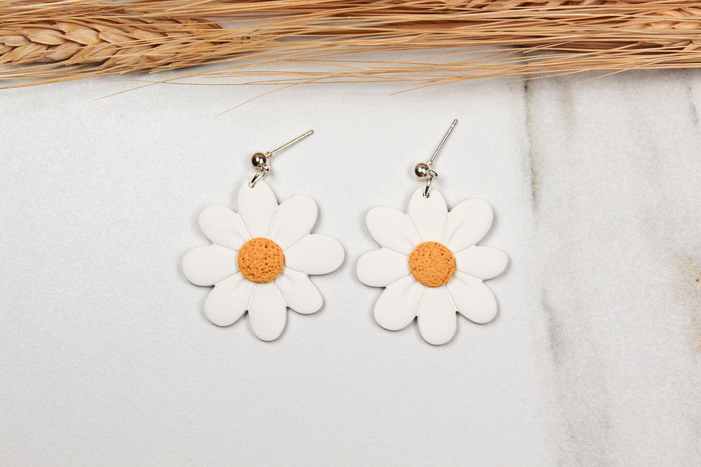 White flower-shaped earrings with yellow centers on a light background