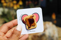 Hand holding a card with a heart-shaped design of a piece of bread with jelly, labeled 'For His Glory'.