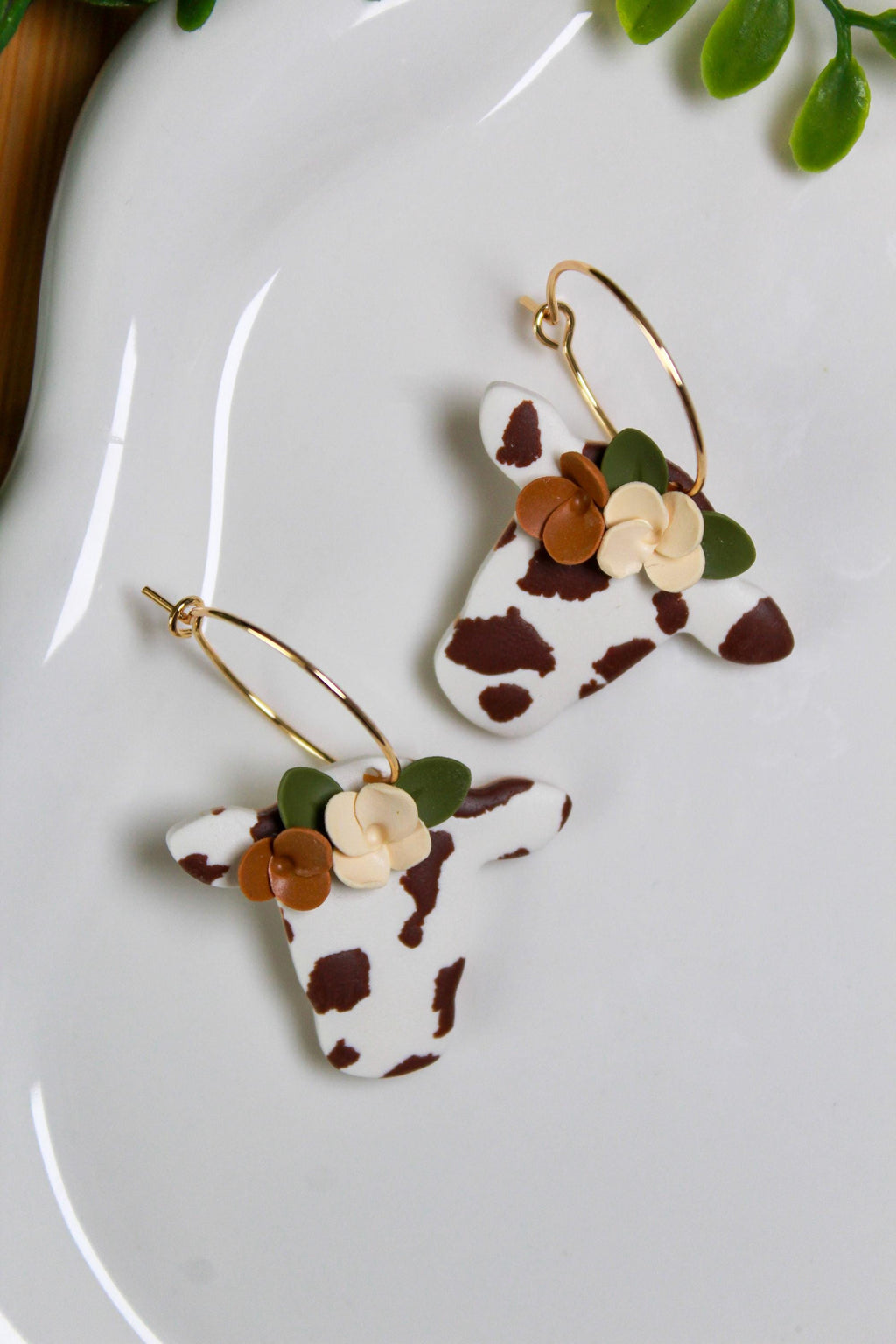 Cow head earrings with floral details on a white plate
