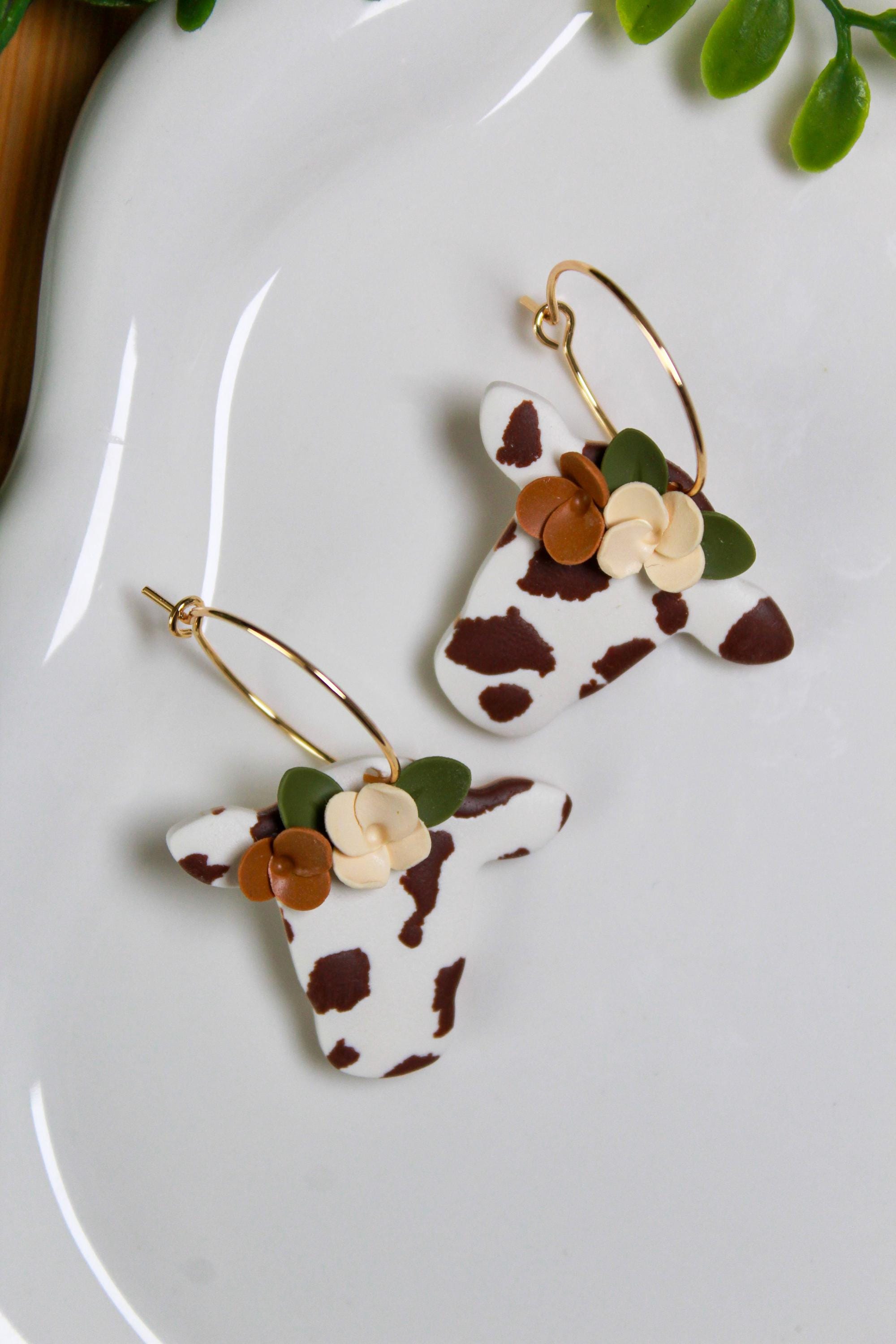 Cow head earrings with floral details on a white plate