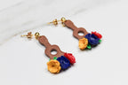 Pair of earrings shaped like guitars with floral tops on a light background