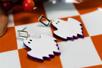 White ghost-shaped earrings with purple accents on a checkered surface